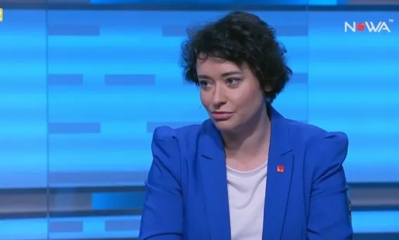 Kobieta w niebieskiej marynarce siedzi w studiu telewizyjnym podczas wywiadu komentującego wystąpienie prezydenta.