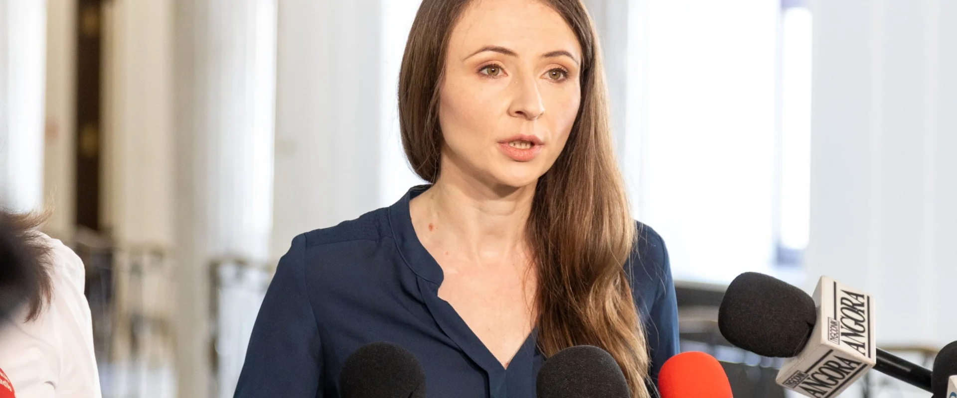 Kobieta w granatowej bluzce przemawia do mikrofonów podczas konferencji prasowej o dekryminalizacji aborcji.