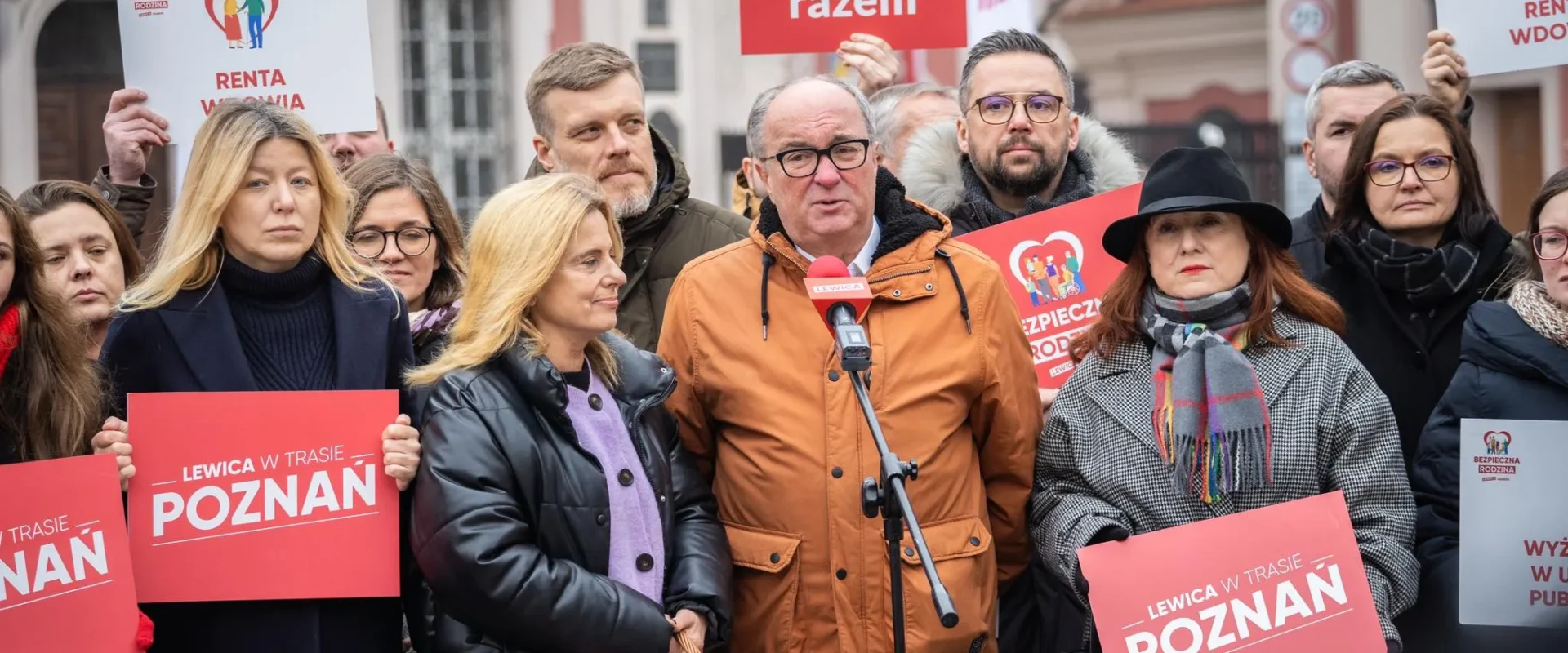 Grupa zwolenników Lewicy na happeningu w Poznaniu trzyma czerwone plakaty „LEWICA w TRASIE POZNAŃ” i gromadzi się wokół mówcy stojącego przy mikrofonie.