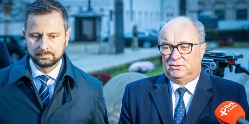 Na zdjęciu widać dwóch mężczyzn w garniturach, stojących na tle budynku, prawdopodobnie podczas wywiadu lub konferencji prasowej.