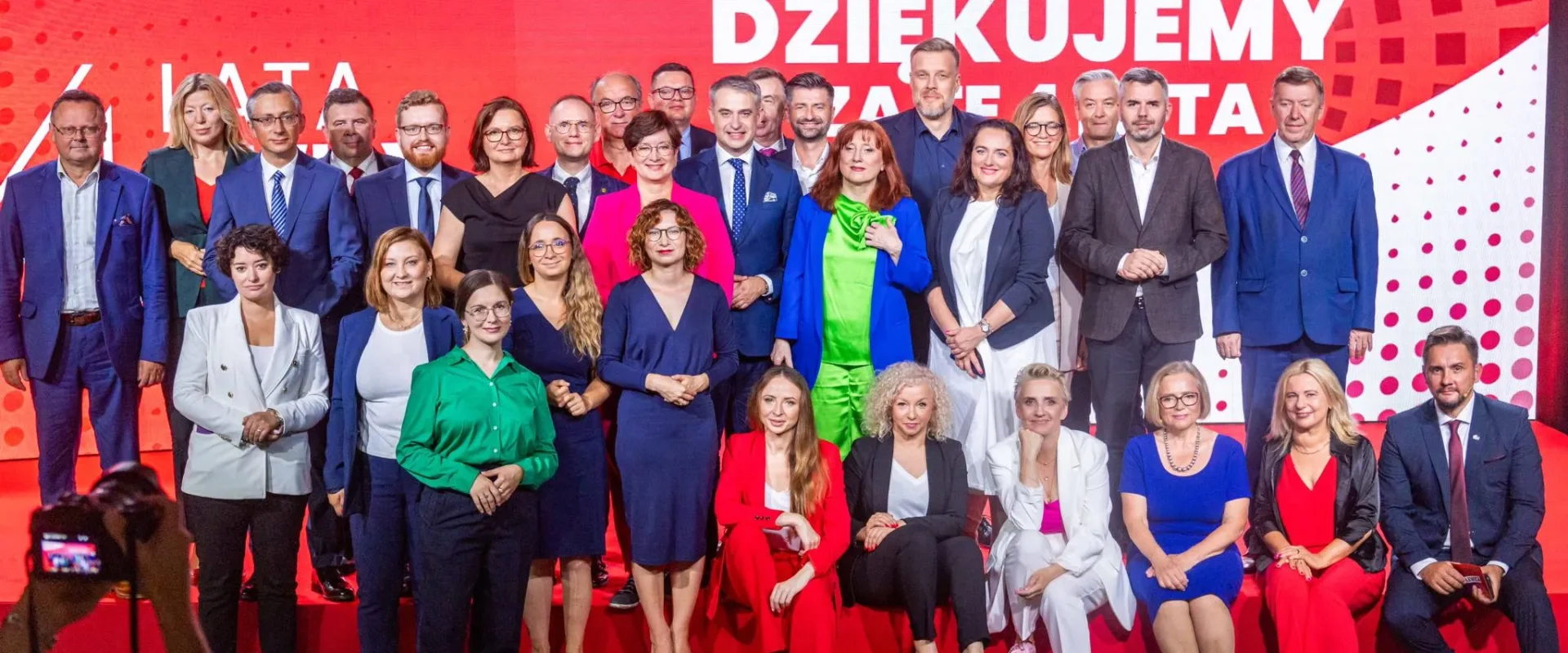 Grupa posłów i posłanek Lewicy stoi na scenie na czerwonym tle z napisem KOALICYJNY KLUB LEWICY, upamiętniając cztery lata działalności Lewicy w Sejmie.