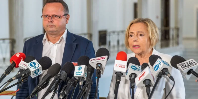 Dwójka polityków stoi przed mikrofonami podczas konferencji prasowej.