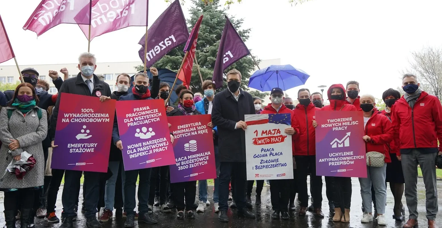 Grupa osób na demonstracji Lewicy trzyma plakaty i flagi z hasłami o prawach pracowniczych i emeryturach podczas obchodów Święta Pracy 1 Maja.