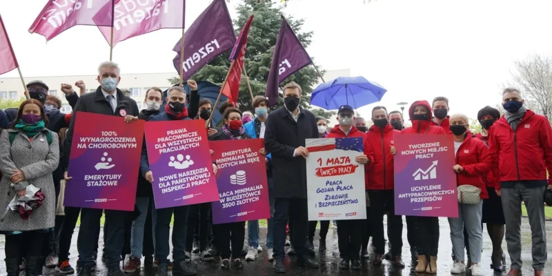 Grupa osób na demonstracji Lewicy trzyma plakaty i flagi z hasłami o prawach pracowniczych i emeryturach podczas obchodów Święta Pracy 1 Maja.
