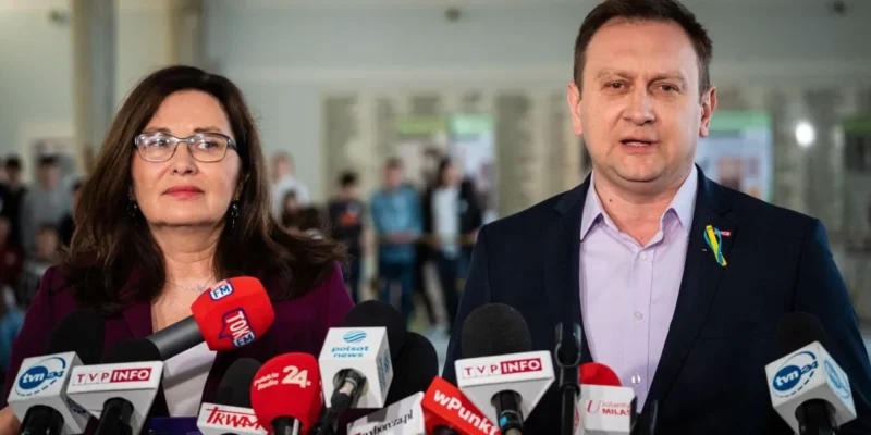 Dwójka polityków stoi przed mikrofonami podczas konferencji prasowej.