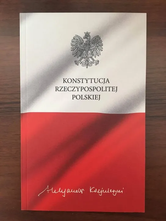 Okładka książki „Konstytucja Rzeczypospolitej Polskiej” z godłem Polski i biało‑czerwonym motywem flagi.