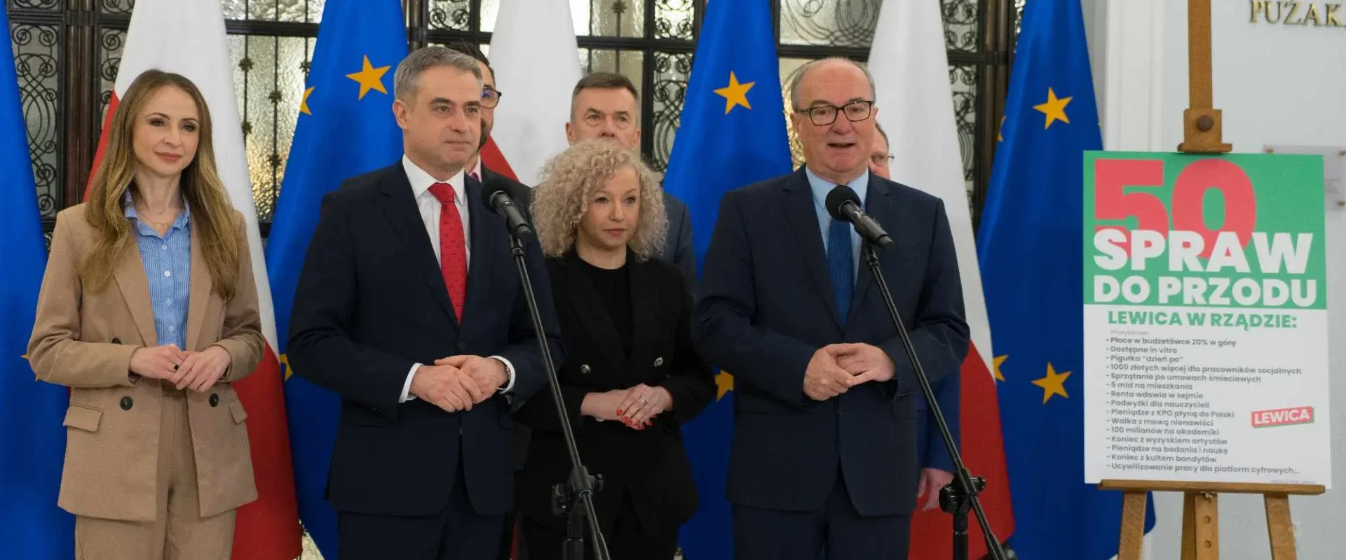 Grupa polityków stoi przy mikrofonach podczas konferencji prasowej, na tle flag Polski i Unii, a obok widnieje plakat „50 Spraw do Przodu” promujący Lewicę w rządzie.