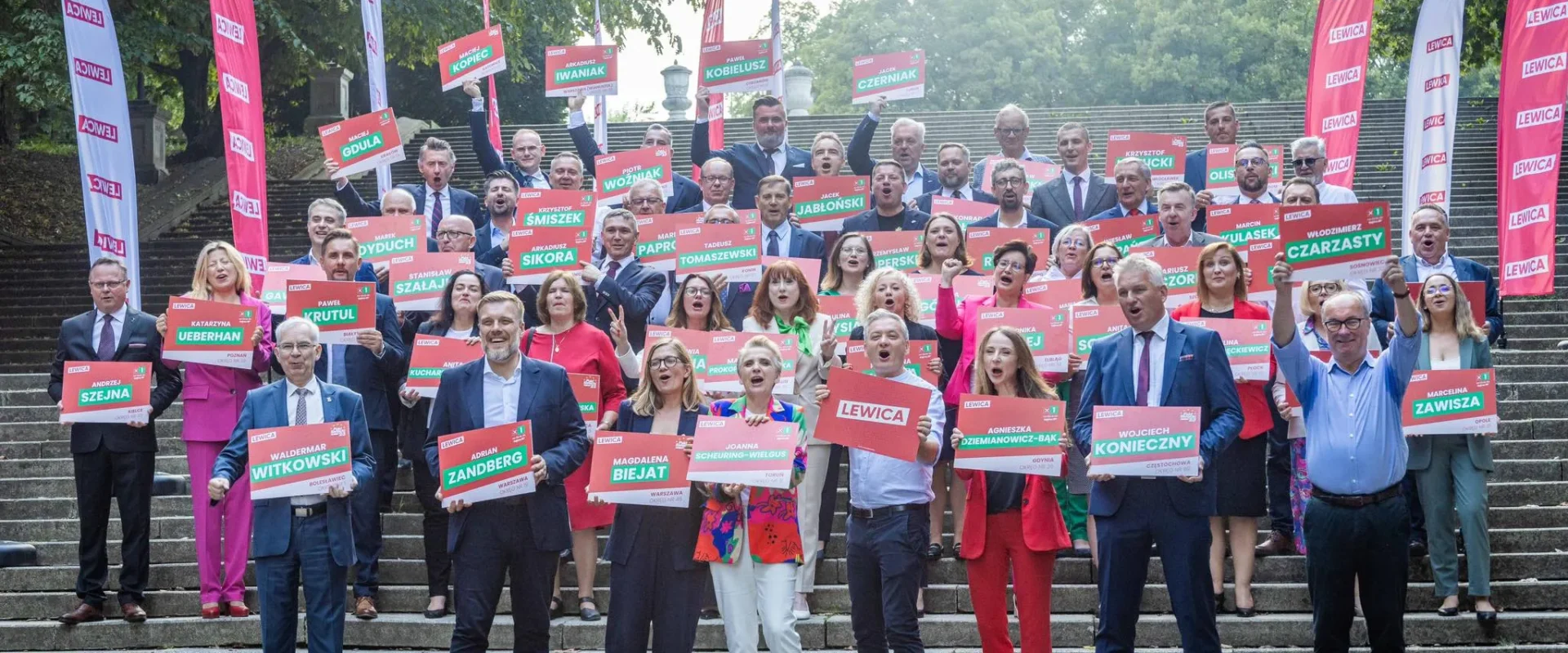 Grupa kandydatów Lewicy na jedynki do Sejmu i Senatu stoi na schodach, trzymając kolorowe plakaty z nazwiskami i logiem Lewicy.
