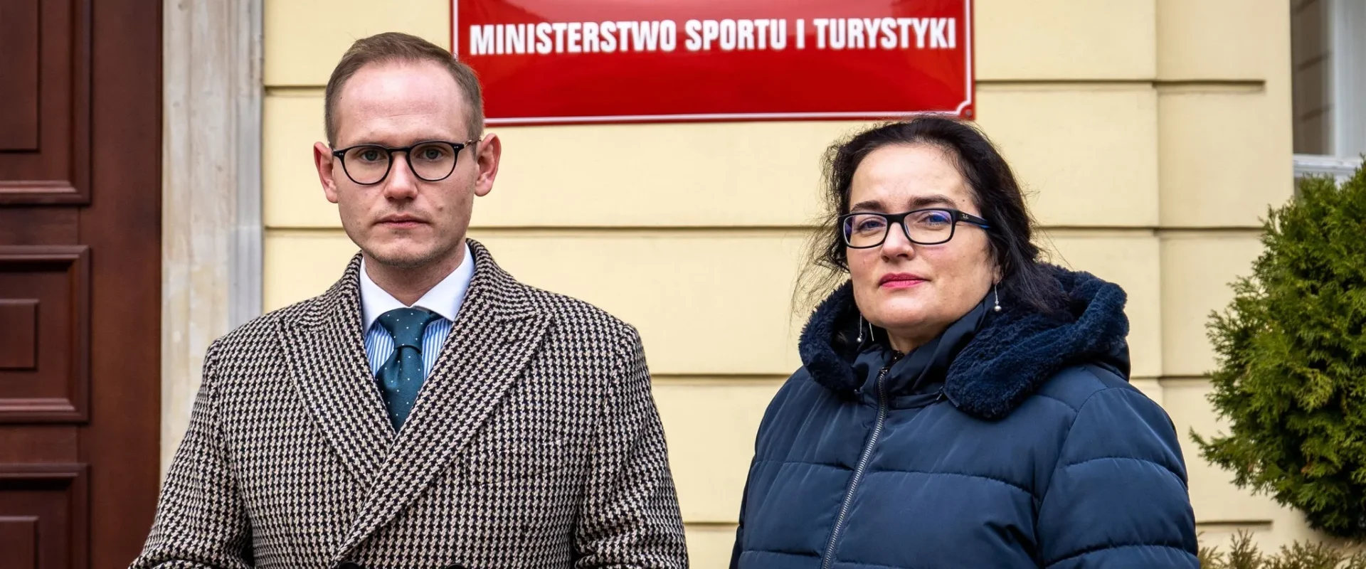 Na zdjęciu widać dwóch ludzi stojących przed budynkiem Ministerstwa Sportu i Turystyki.