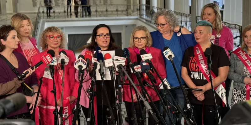 Grupa kobiet‑polityczek Lewicy stoi na konferencji prasowej otoczona licznymi mikrofonami, prezentując projekt zmiany definicji gwałtu i hasło „Tylko TAK” oznaczające zgodę.