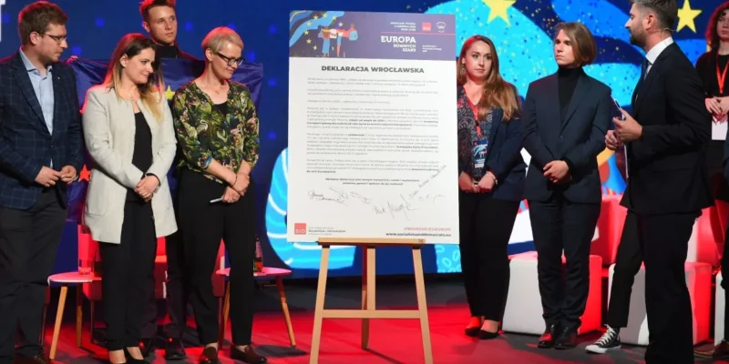 Na zdjęciu przedstawiono grupę ludzi stojących obok dużego dokumentu zatytułowanego "Deklaracja Wrocławska" podczas wydarzenia poświęconego europejskim inicjatywom.