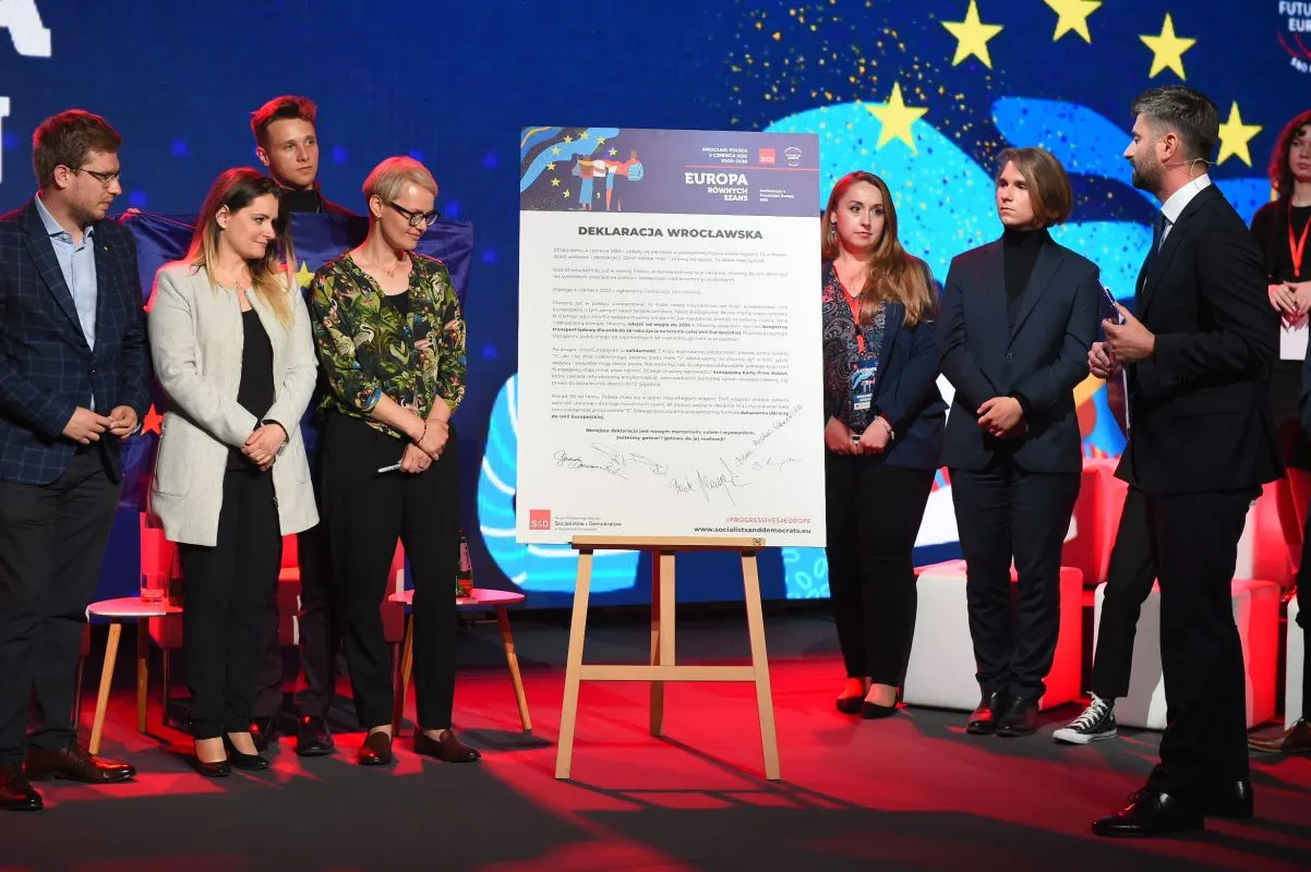 Na zdjęciu przedstawiono grupę ludzi stojących obok dużego dokumentu zatytułowanego "Deklaracja Wrocławska" podczas wydarzenia poświęconego europejskim inicjatywom.