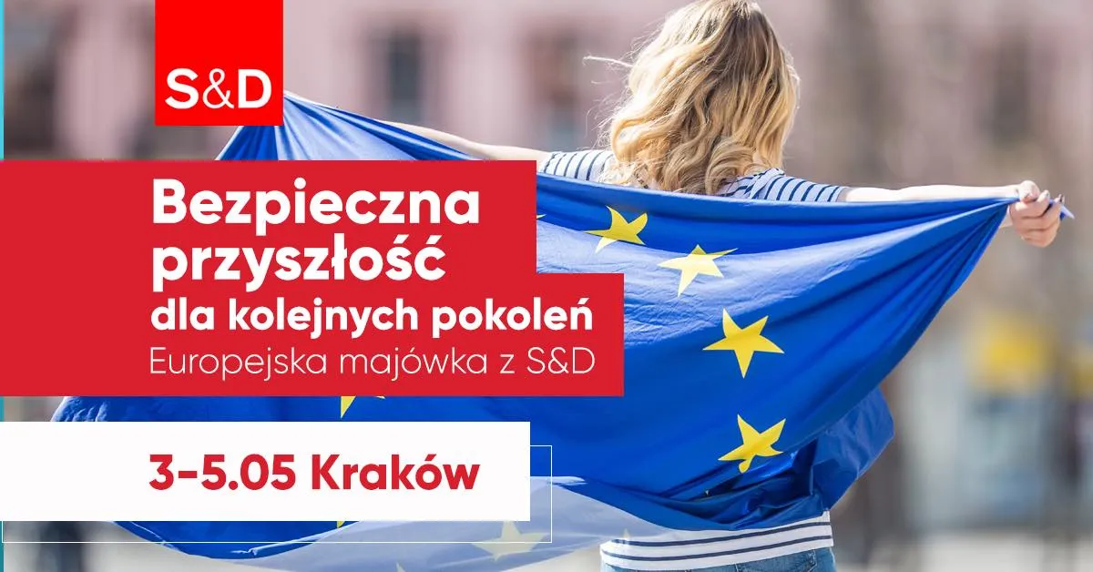 Osoba widziana od tyłu trzyma flagę Unii Europejskiej na tle czerwonego baneru promocyjnego Europejskiej majówki z S&D w Krakowie (3–5 maja).