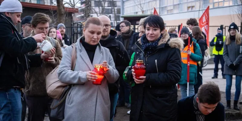 Grupa osób na zewnątrz trzyma zapalone czerwone świeczki podczas 11. rocznicy śmierci Jolanty Brzeskiej.
