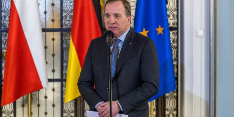 Na zdjęciu widać mężczyznę przemawiającego do mikrofonu, stojącego przed flagami Polski, Niemiec oraz Unii Europejskiej.