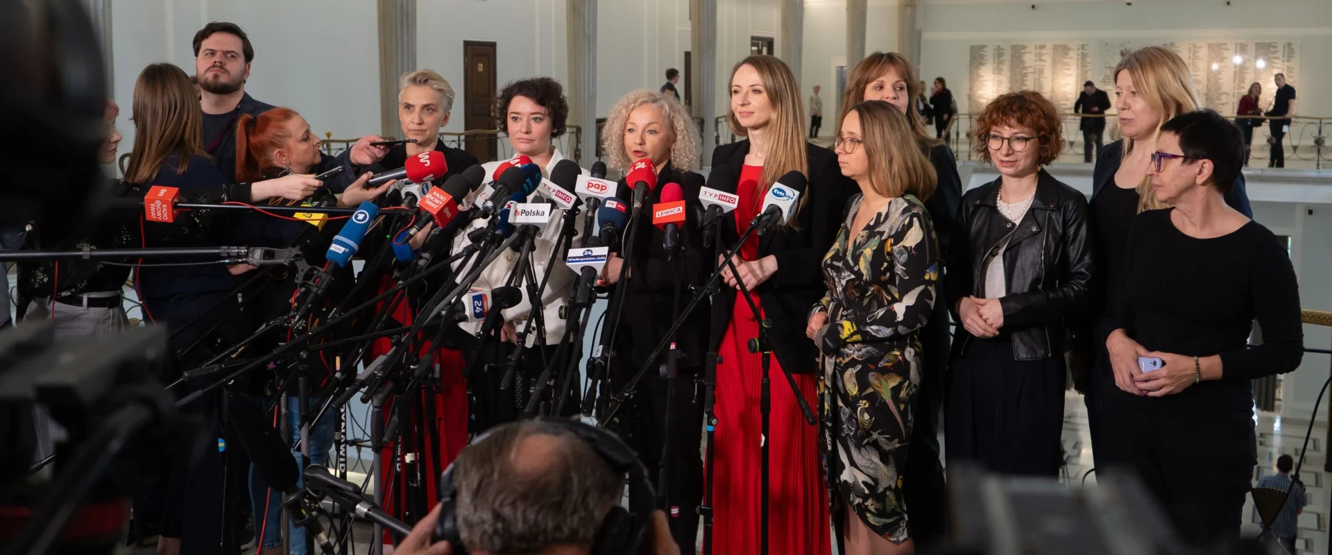 Grupa polityków Lewicy podczas konferencji prasowej w Sejmie, otoczona mikrofonami i kamerami dziennikarzy.