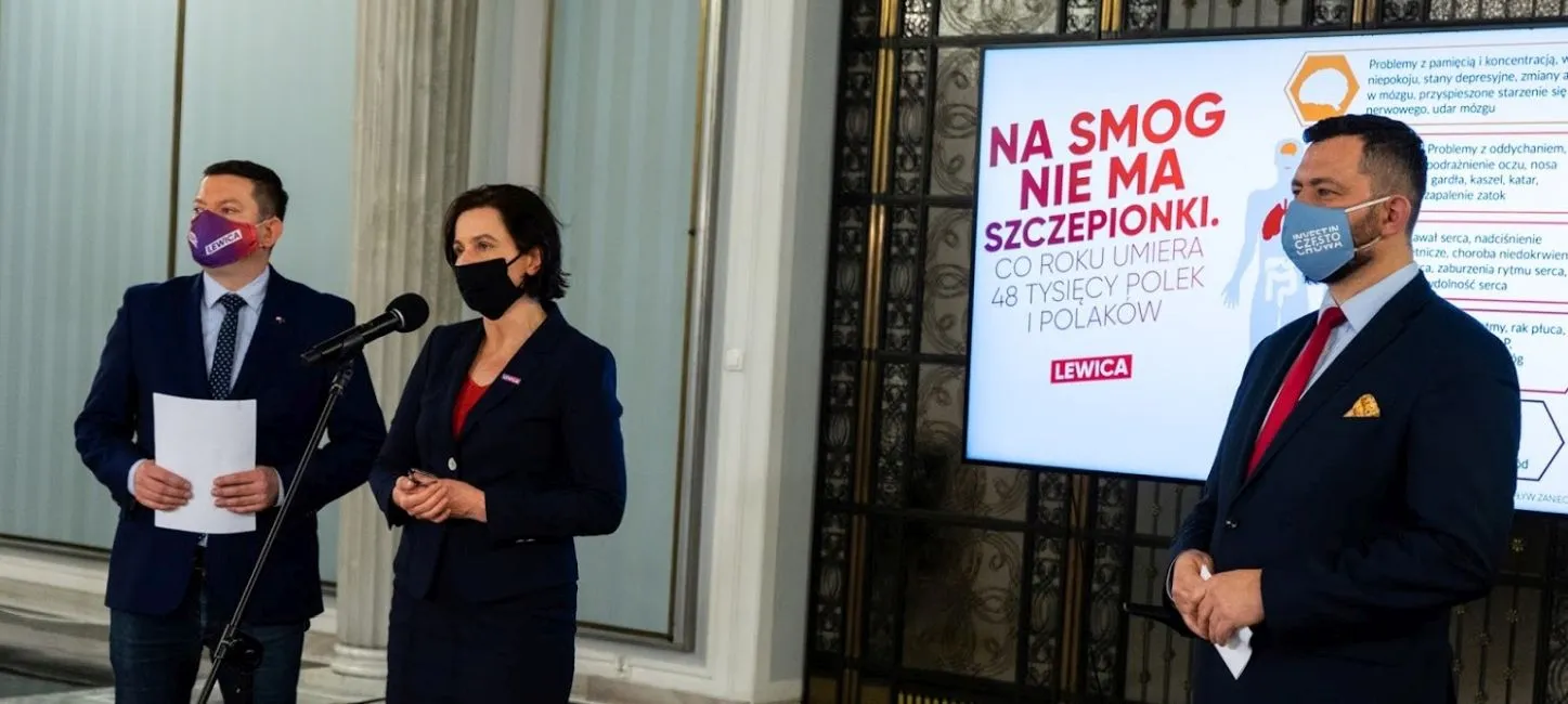 Trzy osoby w garniturach i maseczkach prowadzą konferencję prasową dotyczącą 90% dopłaty do likwidacji kopciuchów w schroniskach górskich, a na ekranie w tle widać materiał Lewicy.