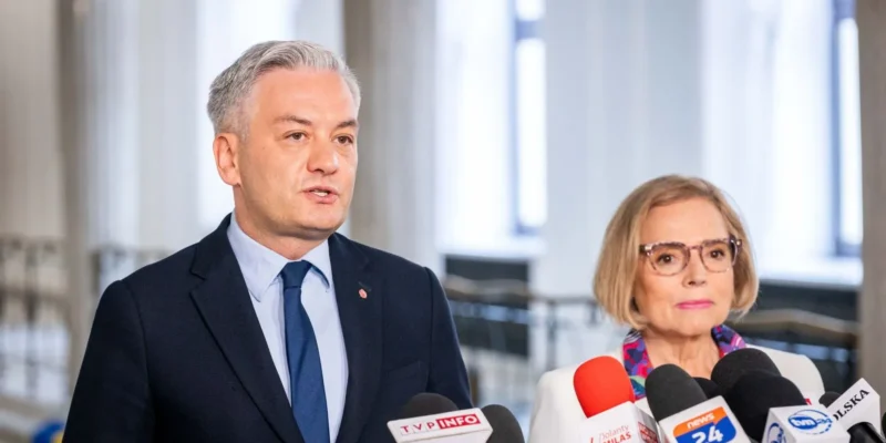 Mężczyzna w garniturze i kobieta z okularami stoją przy mikrofonach podczas konferencji prasowej, omawiając propozycję Lewicy dotyczącą powołania sejmowej Komisji Praw Kobiet.