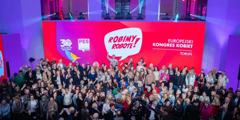 Tłum zgromadzony na Europejskim Kongresie Kobiet w Toruniu, z wieloma osobami pozującymi do zdjęcia przed kolorowym tłem z napisem "Robimy Robotę!".