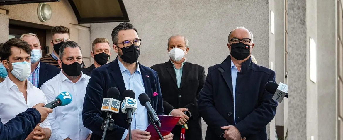 Grupa mężczyzn w maseczkach stoi przed mikrofonami podczas konferencji prasowej, a centralnie ustawiony mówca w granatowym garniturze mówi o otwartej, punktowej współpracy z Agronią.