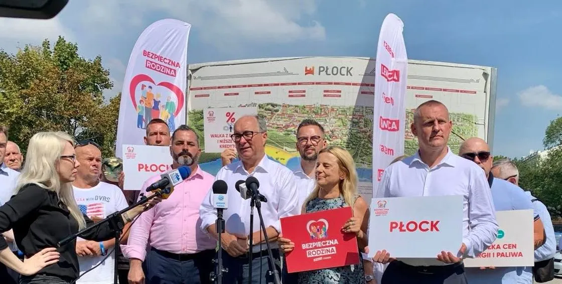 Na zdjęciu przedstawiono grupę osób trzymających transparenty w trakcie wydarzenia promującego bezpieczeństwo rodzin w Płocku.