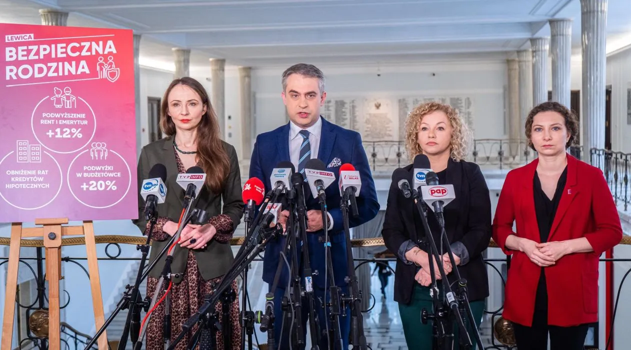 Na zdjęciu widoczna jest konferencja prasowa z czterema osobami stojącymi przed mikrofonami oraz planszą prezentującą propozycje polityczne związane z bezpieczeństwem rodziny.