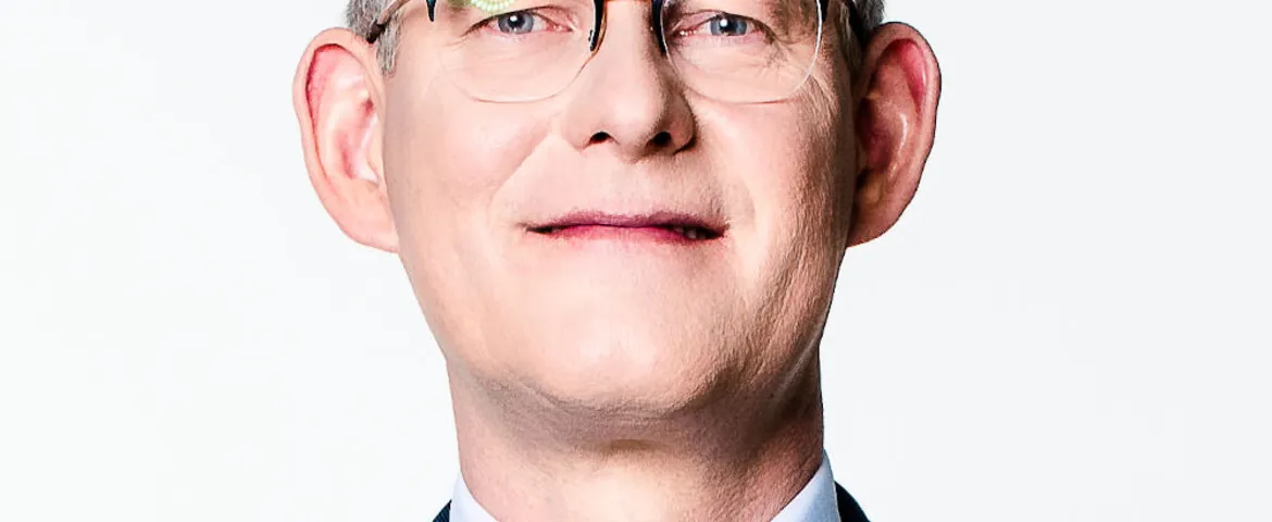 Zbliżenie na dolną część twarzy mężczyzny w okularach, na jasnym tle.