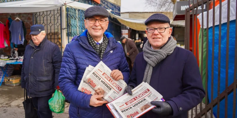 Dwóch starszych mężczyzn w czapkach i okularach trzyma gazety „Renta Wdowy” na targowisku w województwie pomorskim, będąc częścią kampanii Lewicy „Bezpieczna Rodzina”.