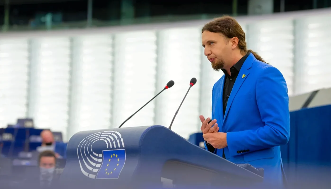 Mężczyzna w niebieskim garniturze przemawia w Parlamencie Europejskim.