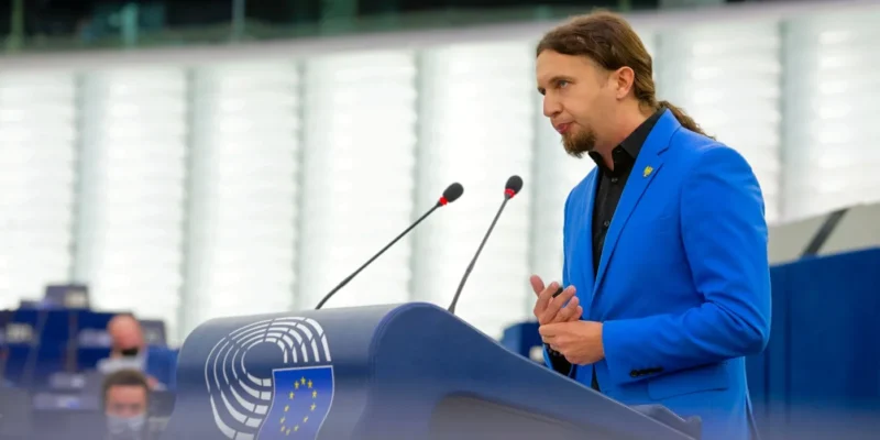 Mężczyzna w niebieskim garniturze przemawia w Parlamencie Europejskim.