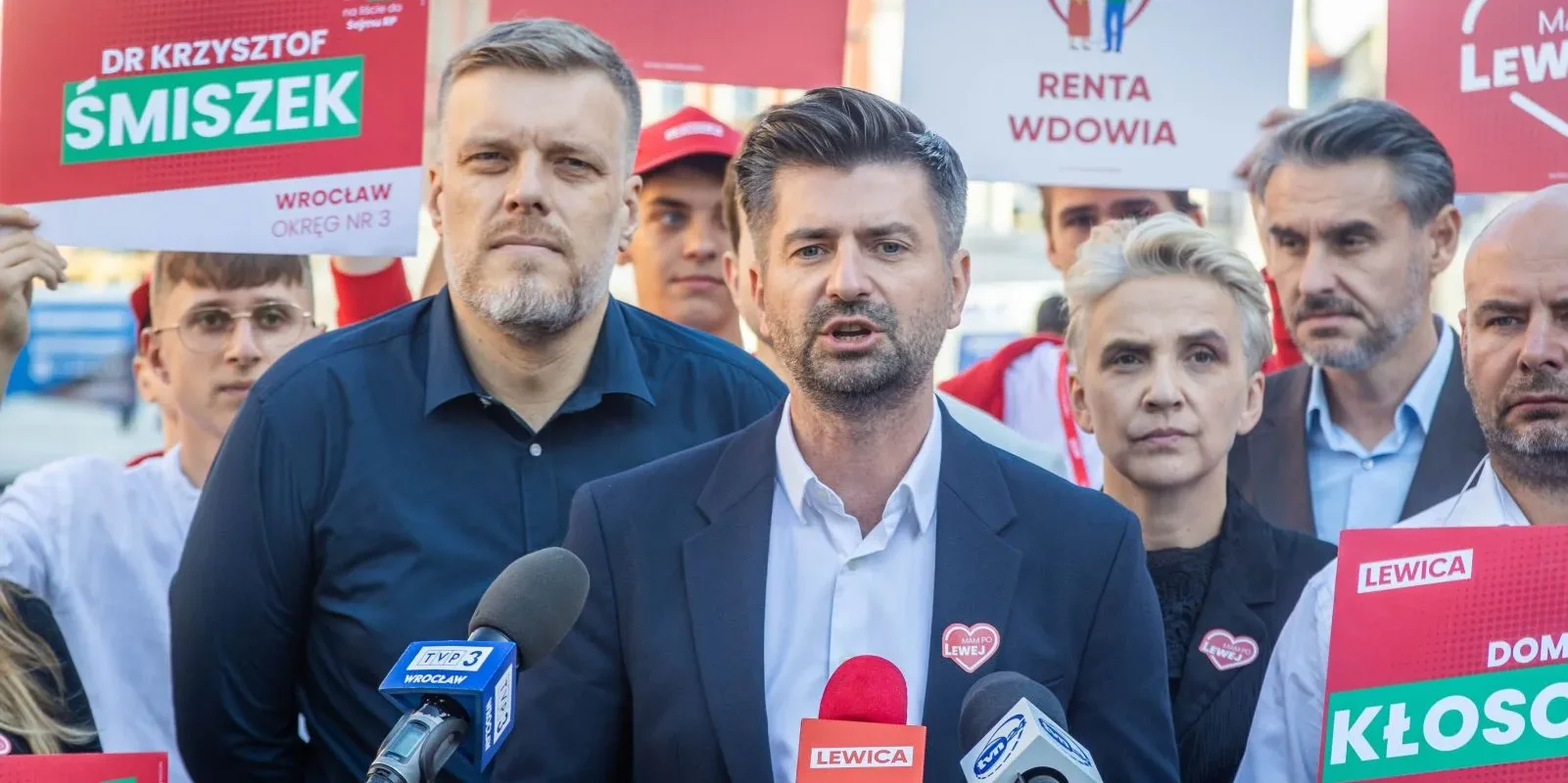 Politycy i zwolennicy Lewicy na wiecu z plakatami domagają się utworzenia Centralnego Biura Monitorowania Policji, przemawiając do mediów.