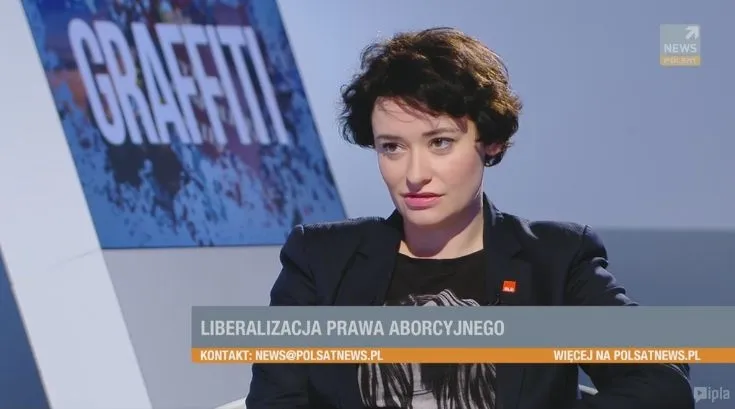 Kobieta siedzi w studiu telewizyjnym podczas rozmowy o liberalizacji prawa aborcyjnego, z widocznym paskiem informacyjnym „LIBERALIZACJA PRAWA ABORCYJNEGO”.