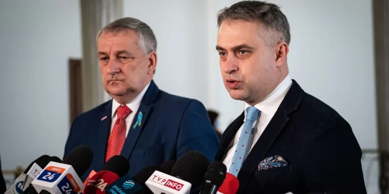 Dwaj mężczyźni podczas konferencji prasowej, stojący przy mikrofonach i wyrażający swoje stanowiska.