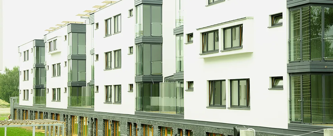 Nowoczesny, biały blok mieszkalny z czarnymi ramami okien i balkonami.