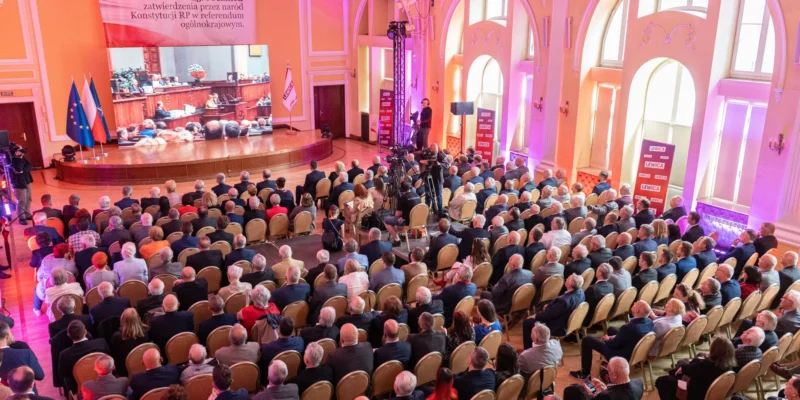 Duża sala konferencyjna wypełniona tłumem uczestników, na scenie prezentacja z flagami UE i Polski i ukazującą 25. rocznicę Konstytucji RP oraz uchwałę Rady Krajowej Nowej Lewicy.