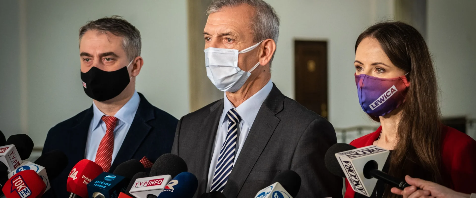 Trzy osoby w garniturach i maseczkach stojące przy licznych mikrofonach podczas konferencji prasowej w sprawie powołania Parlamentarnego Zespołu ds. nauczycielek i nauczycieli oraz pracowników oświaty.