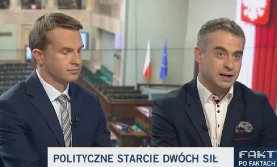 Dwóch mężczyzn w garniturach dyskutuje w studiu telewizyjnym, w tle flaga Polski i pasek z napisem "Polityczne starcie".