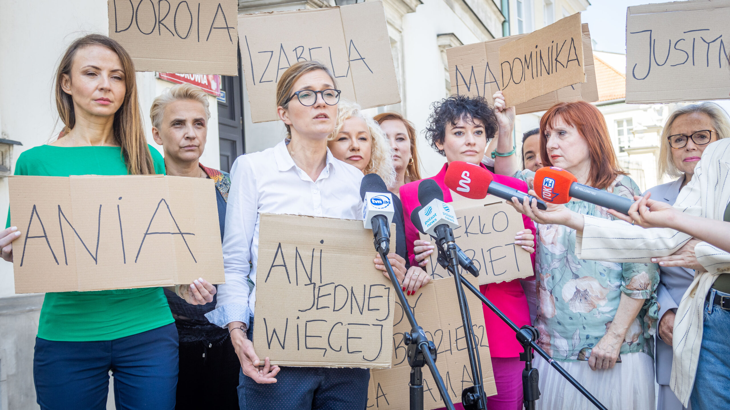 Kobiety na proteście trzymają kartonowe plakaty z napisami i stoją przy mikrofonach, demonstrując przeciw drakońskiemu prawu antyaborcyjnemu w Polsce.