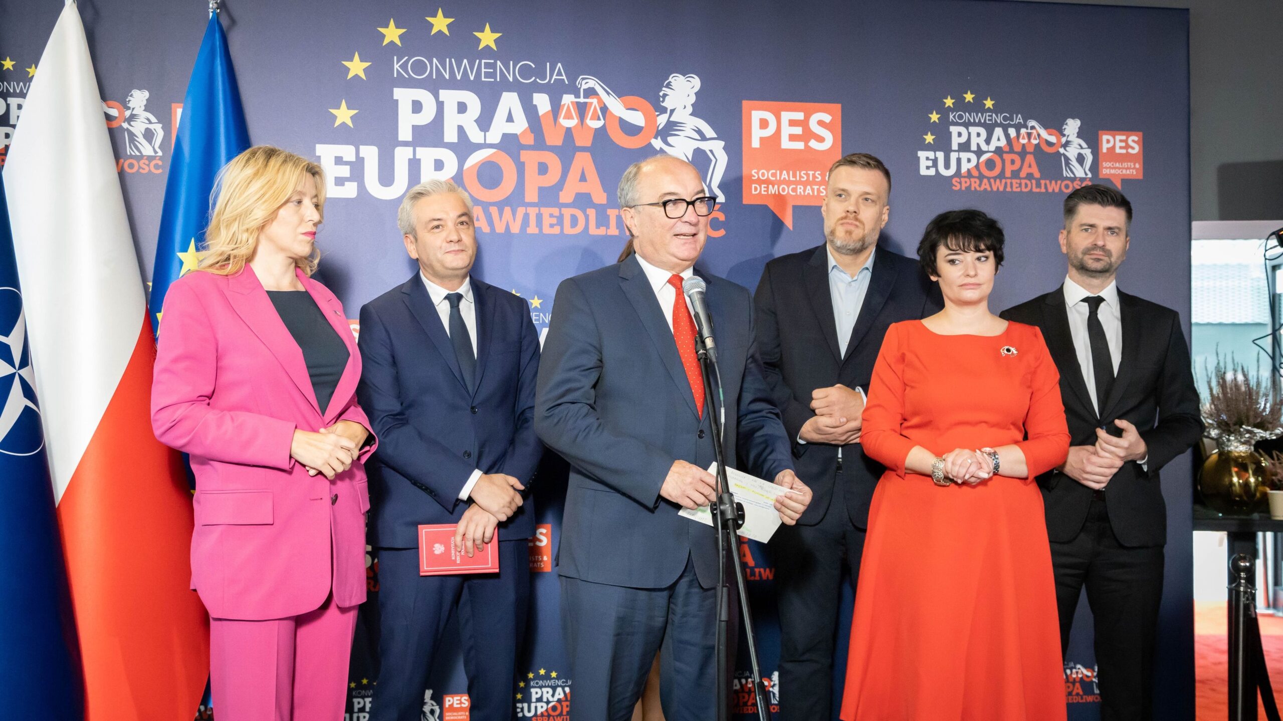 Na zdjęciu grupa polityków stoi przed bannerem z napisem