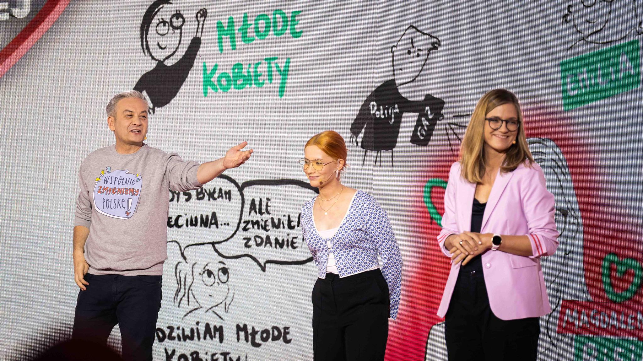 Na scenie stoją trzy osoby podczas wydarzenia „Przyszłość jest teraz! Burza mózgów z młodzieżą”, a za nimi duży ekran z rysunkami i napisem „Młode Kobiety”.