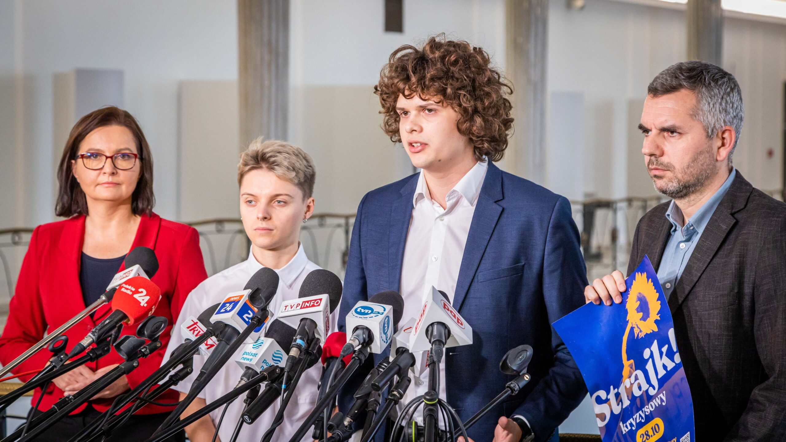 Na zdjęciu cztery osoby stoją przed mikrofonami, prowadząc konferencję prasową na temat strajku.