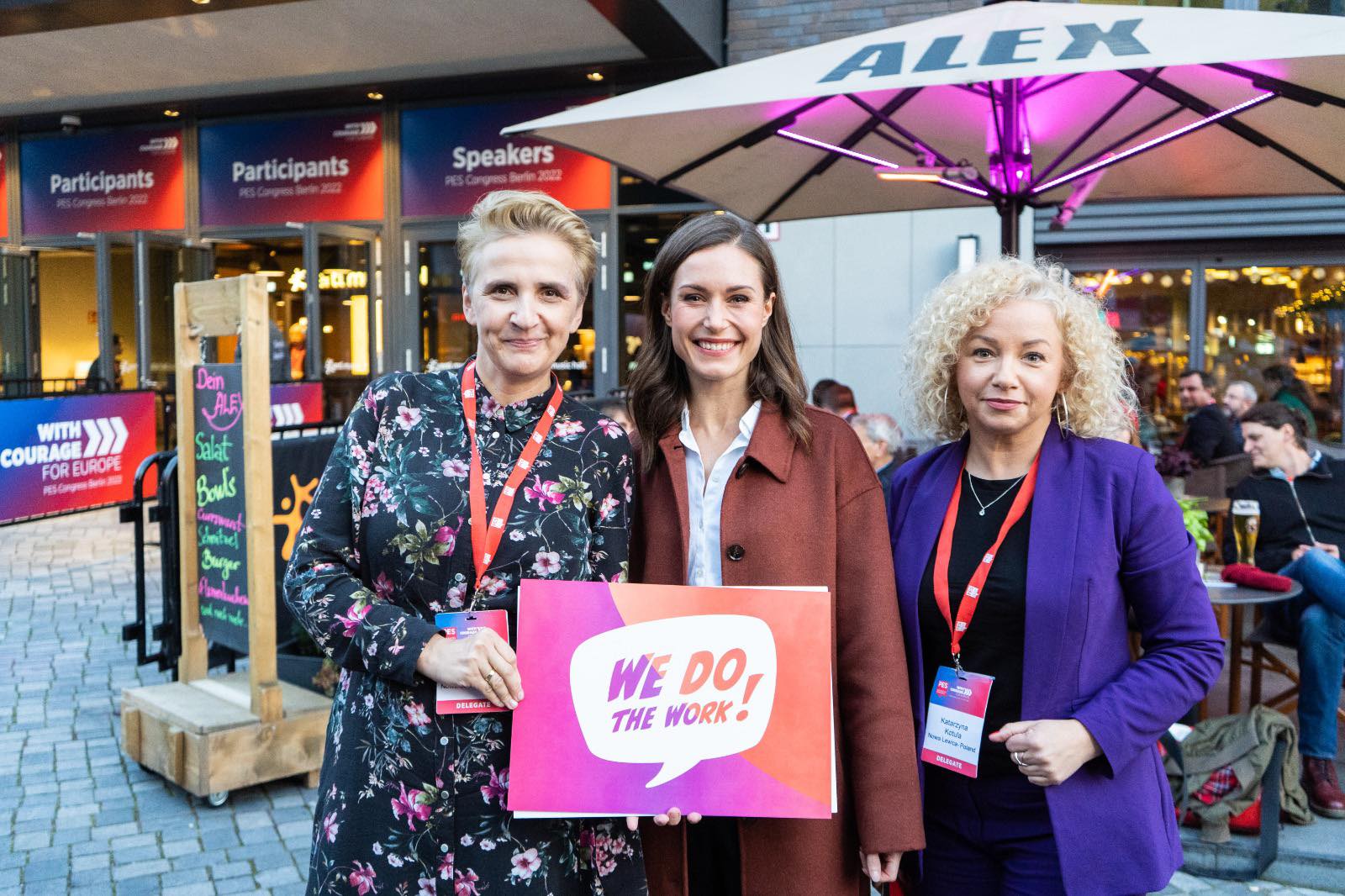Na zdjęciu trzy kobiety pozują z uśmiechami, trzymając za wyglądający na kreatywny plakat z napisem