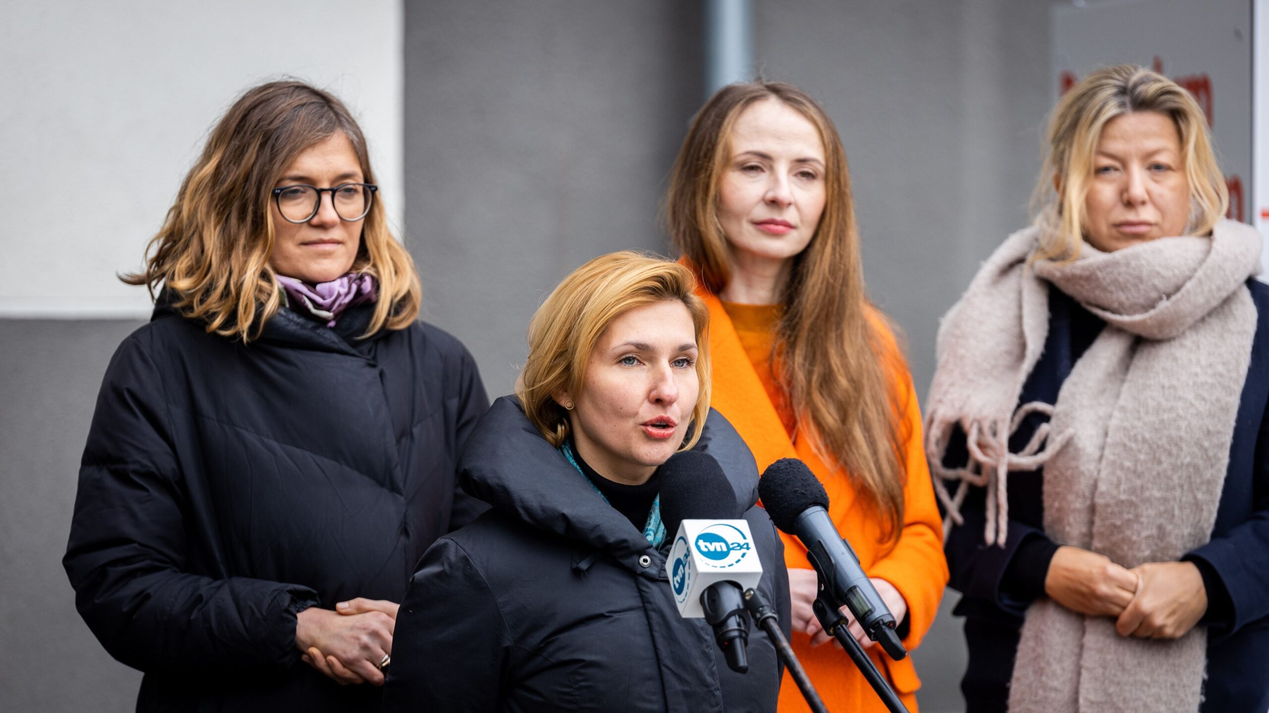 Cztery kobiety stoją na konferencji prasowej dotyczącej zmian w Kodeksie pracy, a jedna z nich przemawia do mikrofonów.