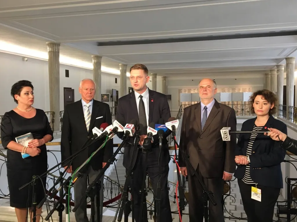 Pięcioro osób stoi za stolikiem z mikrofonami w reprezentacyjnym holu parlamentu podczas konferencji prasowej o ustawie „dezubekizacyjnej”.