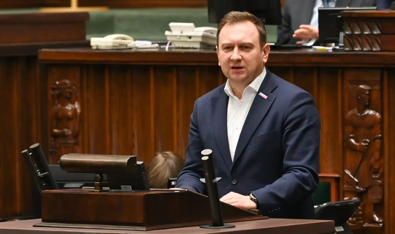 Polityk w garniturze przemawia z mównicy podczas obrad sejmowych, w kontekście Pegasusa i debaty o rzekomym użyciu oprogramowania do zbierania haków na ludzi.