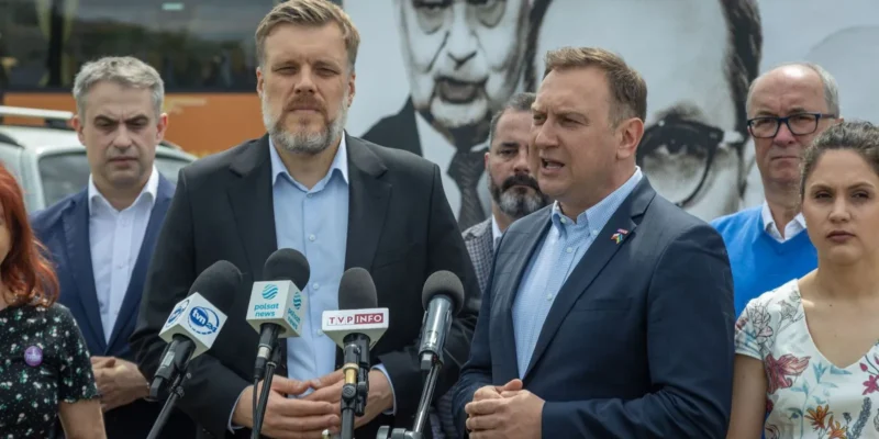 Kilka osób w garniturach przemawia do mediów podczas konferencji prasowej o inflacji w Polsce, stojąc przy mikrofonach.