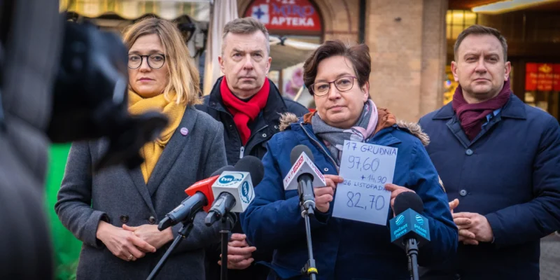 Na zdjęciu przedstawiono konferencję prasową, na której cztery osoby dyskutują na temat danych ekonomicznych, trzymając kartkę z informacjami.