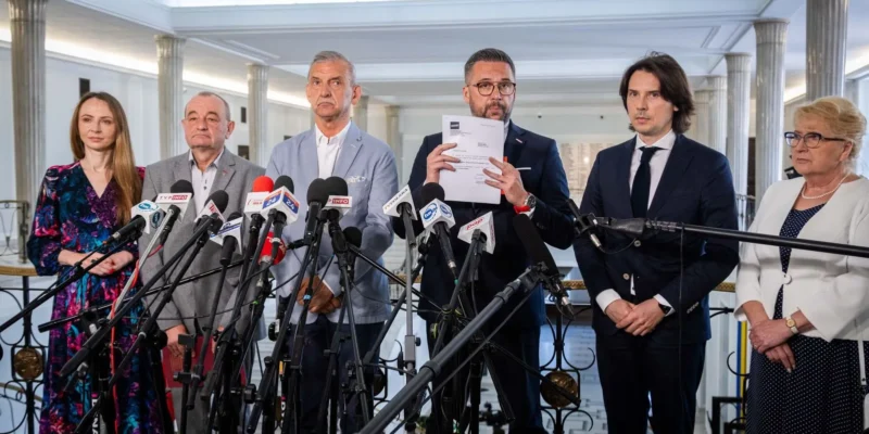 Grupa przedstawicieli ZNP i Lewicy podczas konferencji prasowej stoi za licznymi mikrofonami, trzyma dokument i domaga się 20-procentowej podwyżki dla pracowników nauki i szkolnictwa wyższego.