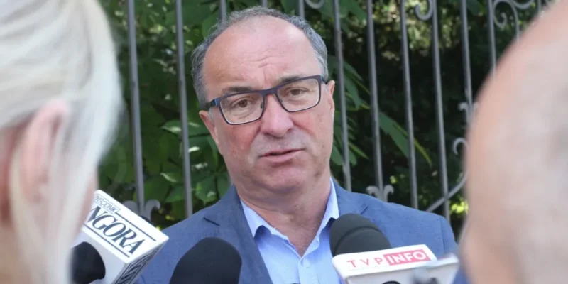 Polityk w marynarce udziela wywiadu otoczony mikrofonami, komentując koniec tej kadencji Sejmu.