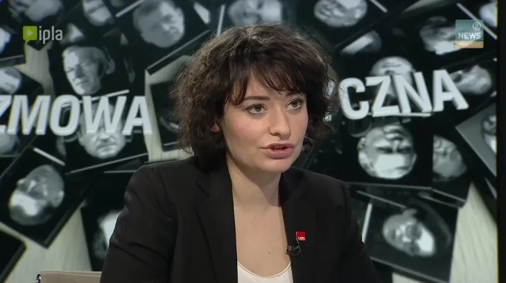 Kobieta w czarnej marynarce z mikrofonem przypiętym do klapy rozmawia w studiu telewizyjnym, a za nią widoczna jest graficzna plansza programu.